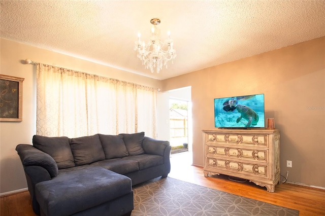 living room featuring baseboards, wood finished floors, an inviting chandelier, and a textured ceiling