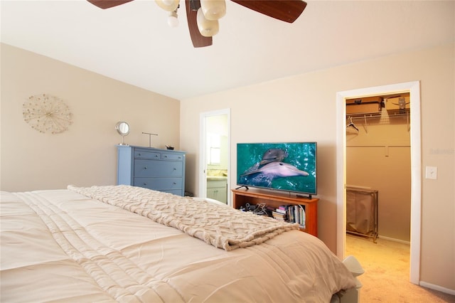 bedroom with ensuite bathroom, a closet, a spacious closet, ceiling fan, and light colored carpet