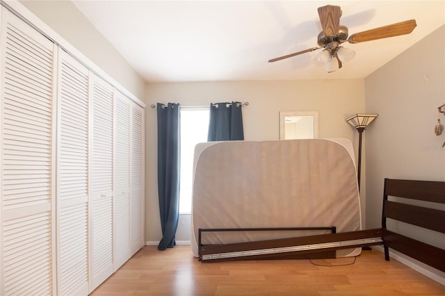 bedroom featuring ceiling fan, baseboards, wood finished floors, and a closet