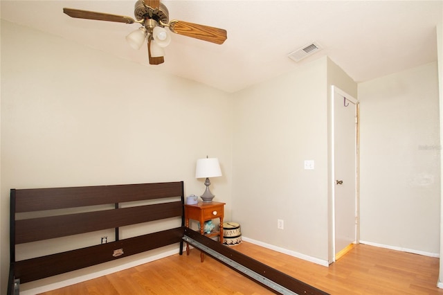 bedroom with baseboards, a ceiling fan, wood finished floors, and visible vents