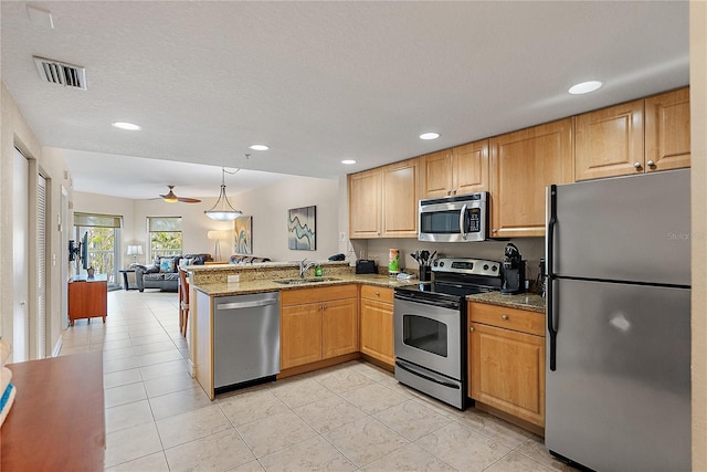 11605 Gulf Blvd Unit 203, Treasure Island, FL 33706 - kitchen featuring stainless steel appliances, a sink, a peninsula, open floor plan, and light stone countertops