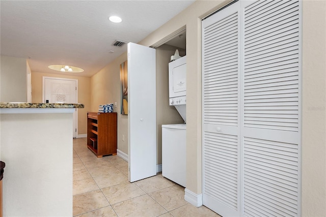 11605 Gulf Blvd Unit 203, Treasure Island, FL 33706 - laundry area with stacked washer / drying machine, light tile patterned floors, and baseboards