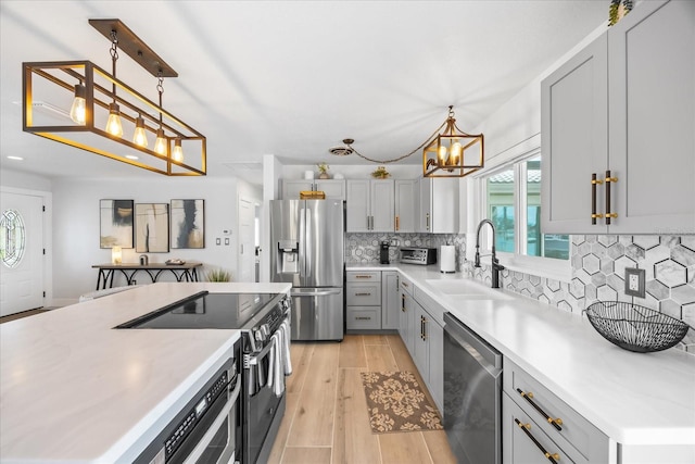 7889 3rd Ave S, Saint Petersburg, FL 33707 - kitchen with stainless steel appliances, a sink, gray cabinets, a chandelier, and light countertops