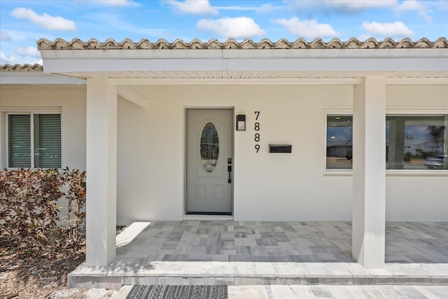7889 3rd Ave S, Saint Petersburg, FL 33707 - doorway to property with stucco siding and a tiled roof
