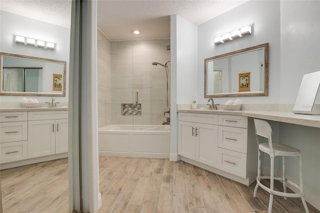 bathroom featuring two vanities, wood finished floors, a textured ceiling, and a sink