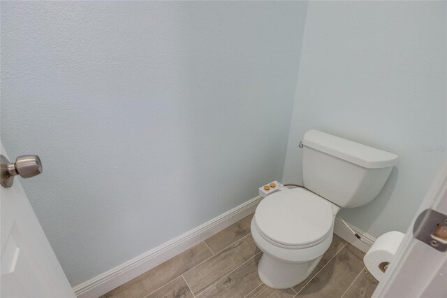 bathroom featuring wood finish floors, toilet, and baseboards