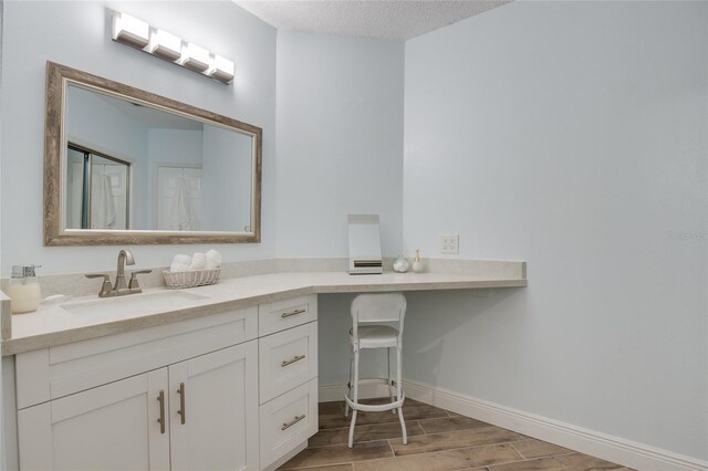 bathroom with baseboards, wood finished floors, a textured ceiling, and vanity