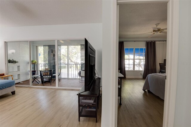bedroom with a textured ceiling, wood finished floors, access to exterior, and ceiling fan