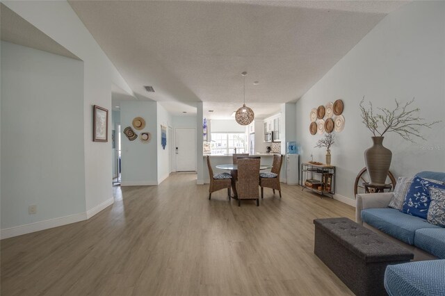 living room featuring baseboards, light wood-style flooring, and visible vents