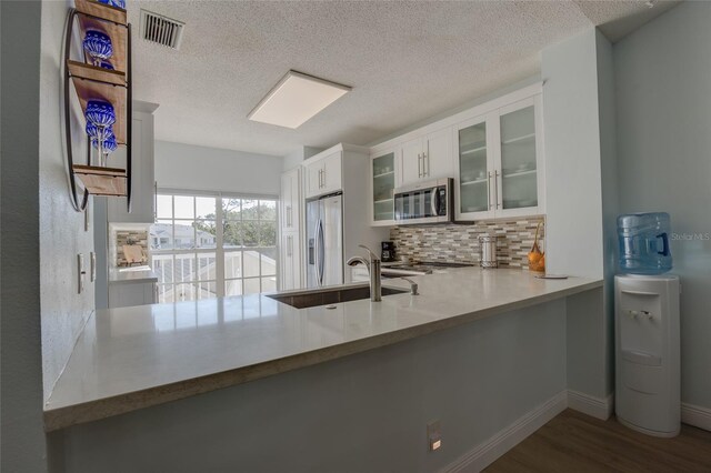 kitchen with wood finished floors, a sink, backsplash, appliances with stainless steel finishes, and visible vents