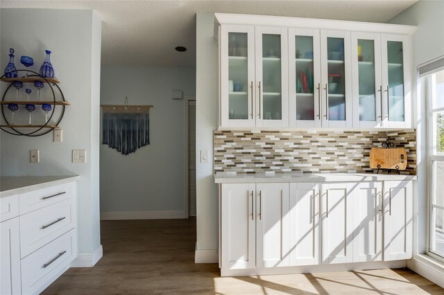 kitchen featuring light countertops, baseboards, tasteful backsplash, and dark wood finished floors