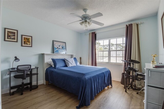 bedroom featuring wood finished floors, a textured ceiling, baseboards, and ceiling fan
