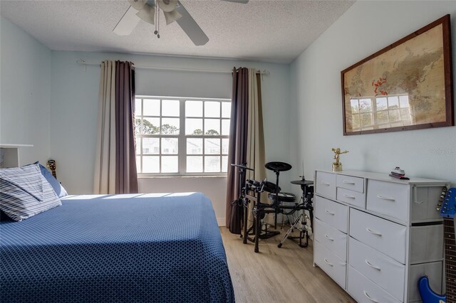 bedroom with ceiling fan, a textured ceiling, and light wood-style flooring