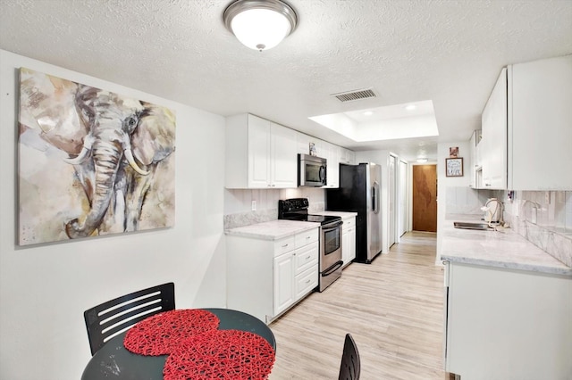 13902 Bardmoor Pl Unit B, Tampa, FL 33618 - kitchen with appliances with stainless steel finishes, a sink, white cabinets, a textured ceiling, and light wood finished floors