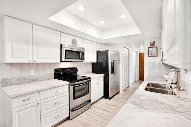 13902 Bardmoor Pl Unit B, Tampa, FL 33618 - kitchen featuring appliances with stainless steel finishes, a sink, a tray ceiling, light wood-type flooring, and white cabinets