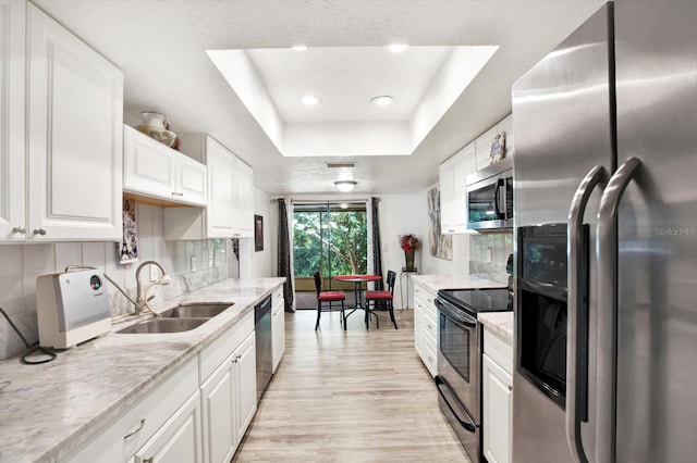 13902 Bardmoor Pl Unit B, Tampa, FL 33618 - kitchen with appliances with stainless steel finishes, a sink, a raised ceiling, white cabinets, and light wood-type flooring