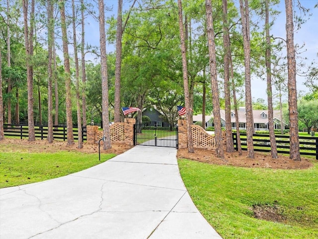 view of home's community with driveway, a gate, a lawn, and a fenced front yard