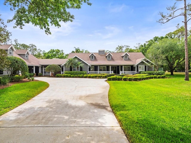 view of front facade with a front lawn, covered porch, and curved driveway