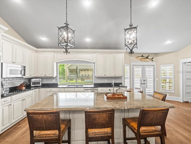kitchen with pendant lighting, a kitchen bar, decorative backsplash, and vaulted ceiling