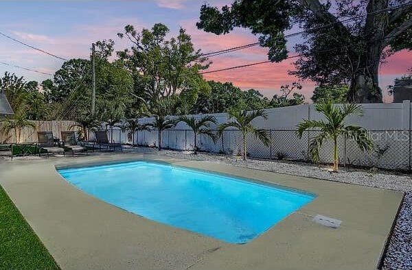 pool at dusk featuring a patio, a fenced backyard, and a fenced in pool