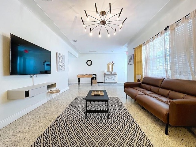 living area featuring an inviting chandelier, speckled floor, baseboards, and visible vents