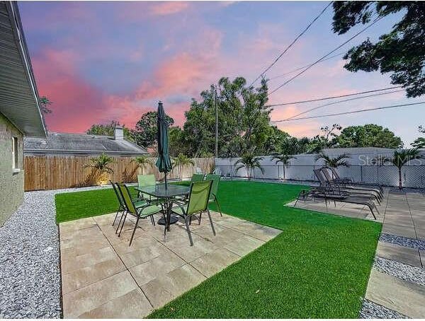 view of yard featuring a patio area, outdoor dining area, and a fenced backyard