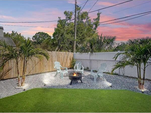 yard at dusk with a fire pit and a fenced backyard