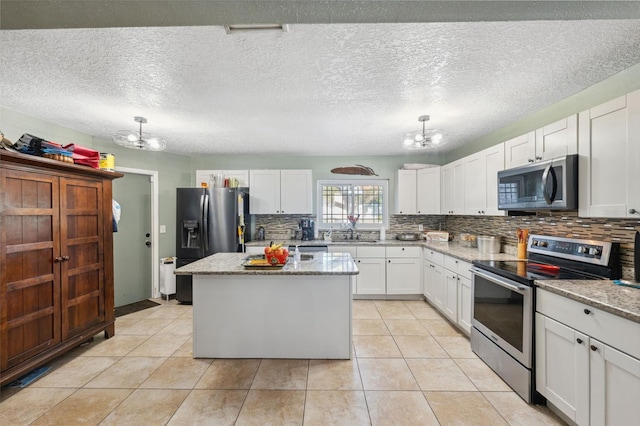 2906 Beagle Pl, Seffner, FL 33584 - kitchen featuring an inviting chandelier, a center island, backsplash, white cabinets, and appliances with stainless steel finishes
