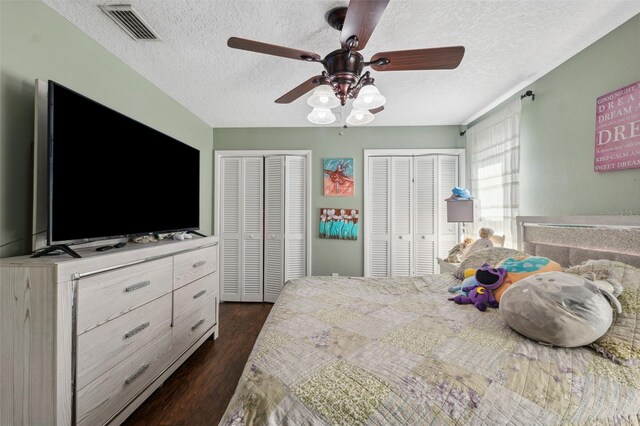 2906 Beagle Pl, Seffner, FL 33584 - bedroom with a textured ceiling, a ceiling fan, visible vents, dark wood-style flooring, and multiple closets