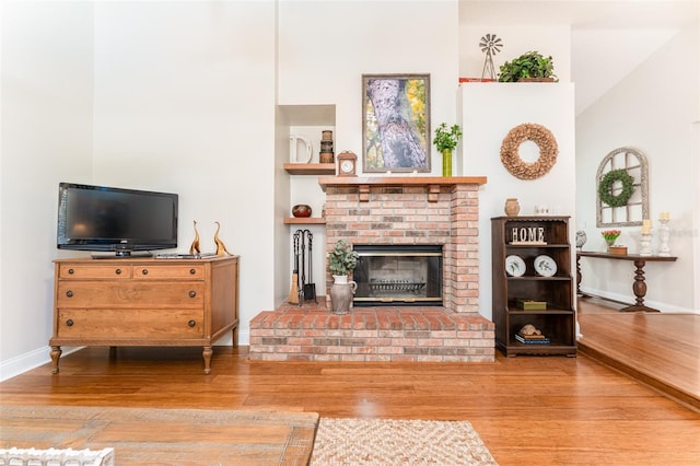 living room featuring wood finished floors, a fireplace, and baseboards