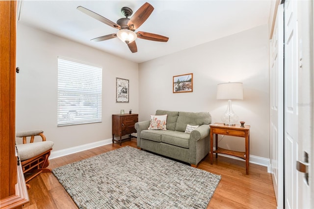 living room with light wood finished floors, baseboards, and a ceiling fan