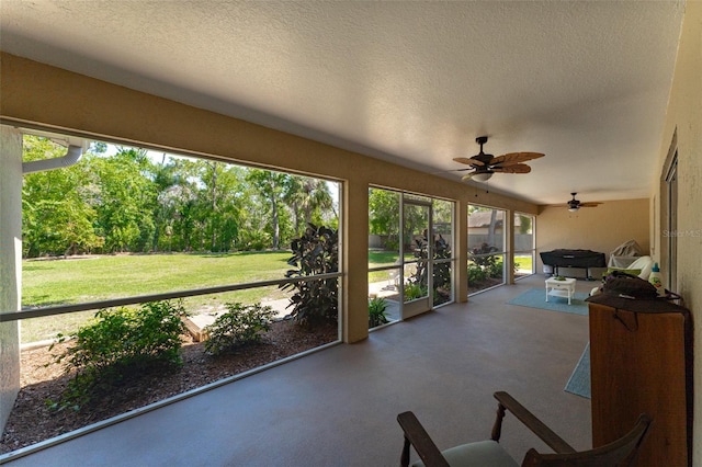 sunroom / solarium with finished concrete flooring, a textured ceiling, and ceiling fan