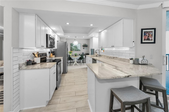 1600 Gulf Blvd Unit 212, Clearwater Beach, FL 33767 - kitchen with appliances with stainless steel finishes, tasteful backsplash, white cabinets, a peninsula, and a breakfast bar