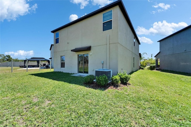 back of property with cooling unit, a gazebo, stucco siding, and a yard