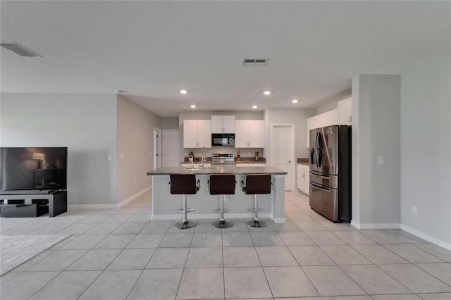 kitchen featuring white cabinets, visible vents, a kitchen bar, and appliances with stainless steel finishes