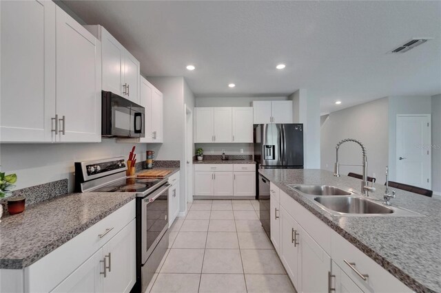 kitchen featuring visible vents, light tile patterned floors, a sink, black microwave, and stainless steel electric range