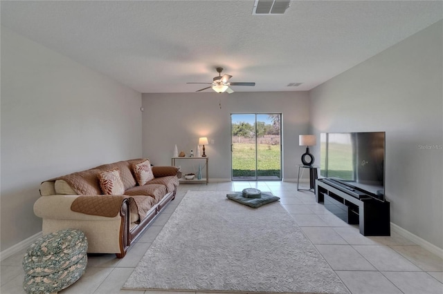 living room featuring baseboards, light tile patterned floors, a textured ceiling, visible vents, and ceiling fan