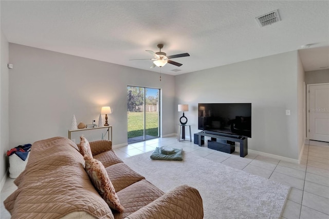 living area with light tile patterned floors, a textured ceiling, a ceiling fan, visible vents, and baseboards