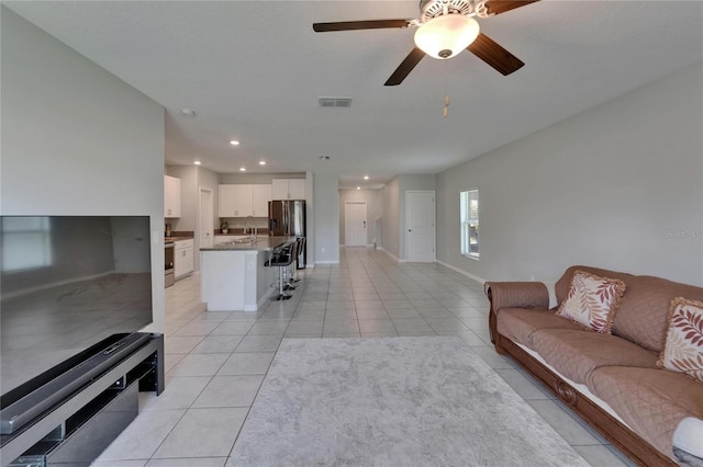living area with light tile patterned floors, a ceiling fan, visible vents, recessed lighting, and baseboards