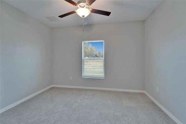 carpeted spare room with visible vents, baseboards, and a ceiling fan