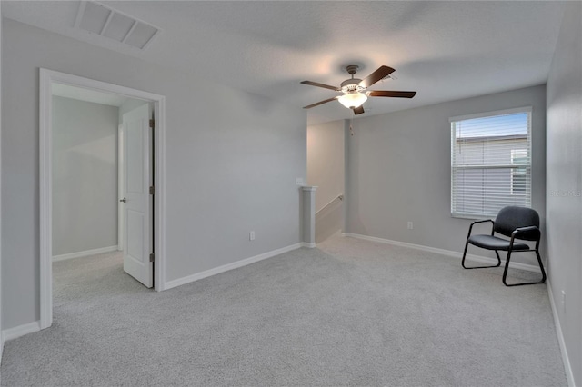 unfurnished room with a ceiling fan, visible vents, carpet floors, an upstairs landing, and baseboards