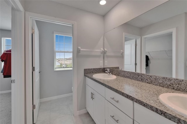 full bathroom featuring double vanity, a sink, tile patterned flooring, and baseboards