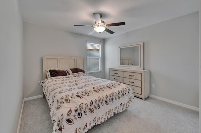 bedroom featuring light colored carpet, baseboards, and a ceiling fan