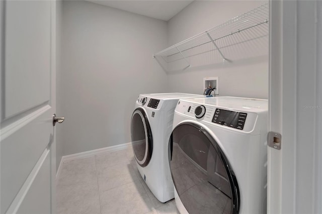 laundry area featuring washer and dryer, laundry area, light tile patterned floors, and baseboards