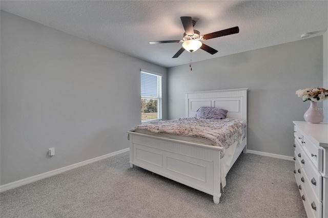 bedroom featuring light carpet, baseboards, and a textured ceiling