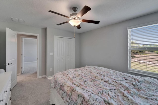 bedroom featuring a closet, light colored carpet, a ceiling fan, visible vents, and baseboards