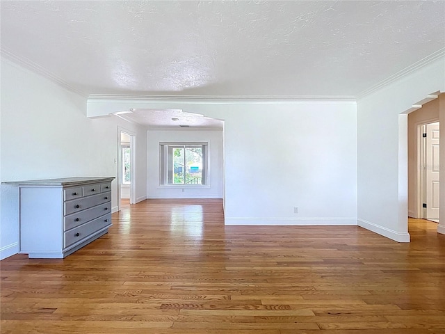 6920 Bougainvilla Ave S, Saint Petersburg, FL 33707 - unfurnished living room featuring arched walkways, a textured ceiling, light wood-type flooring, ornamental molding, and baseboards