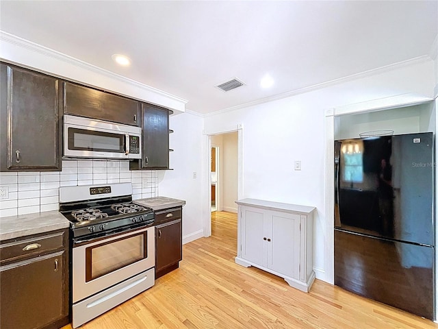 6920 Bougainvilla Ave S, Saint Petersburg, FL 33707 - kitchen with crown molding, appliances with stainless steel finishes, decorative backsplash, and dark brown cabinets
