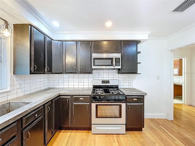 6920 Bougainvilla Ave S, Saint Petersburg, FL 33707 - kitchen featuring visible vents, appliances with stainless steel finishes, crown molding, light wood finished floors, and backsplash