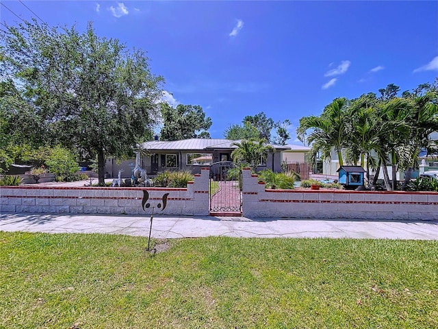 6920 Bougainvilla Ave S, Saint Petersburg, FL 33707 - view of front facade with a fenced front yard, a front yard, metal roof, and a gate